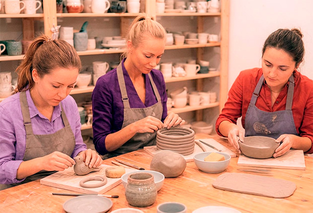 3 Frauen modellieren Objekte aus Ton in einer Keramikwerkstatt